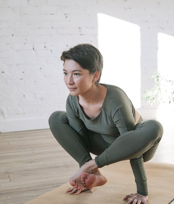 Woman in a calm yoga pose in a brightly lit room.
